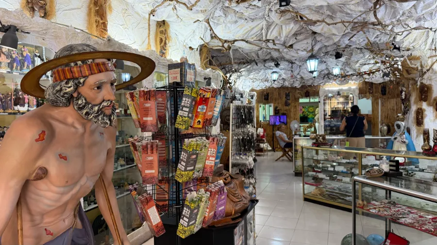 Interior de Bazar Kalunga: imágenes de santos, inciensos y vitrinas bajo el techo de la tienda