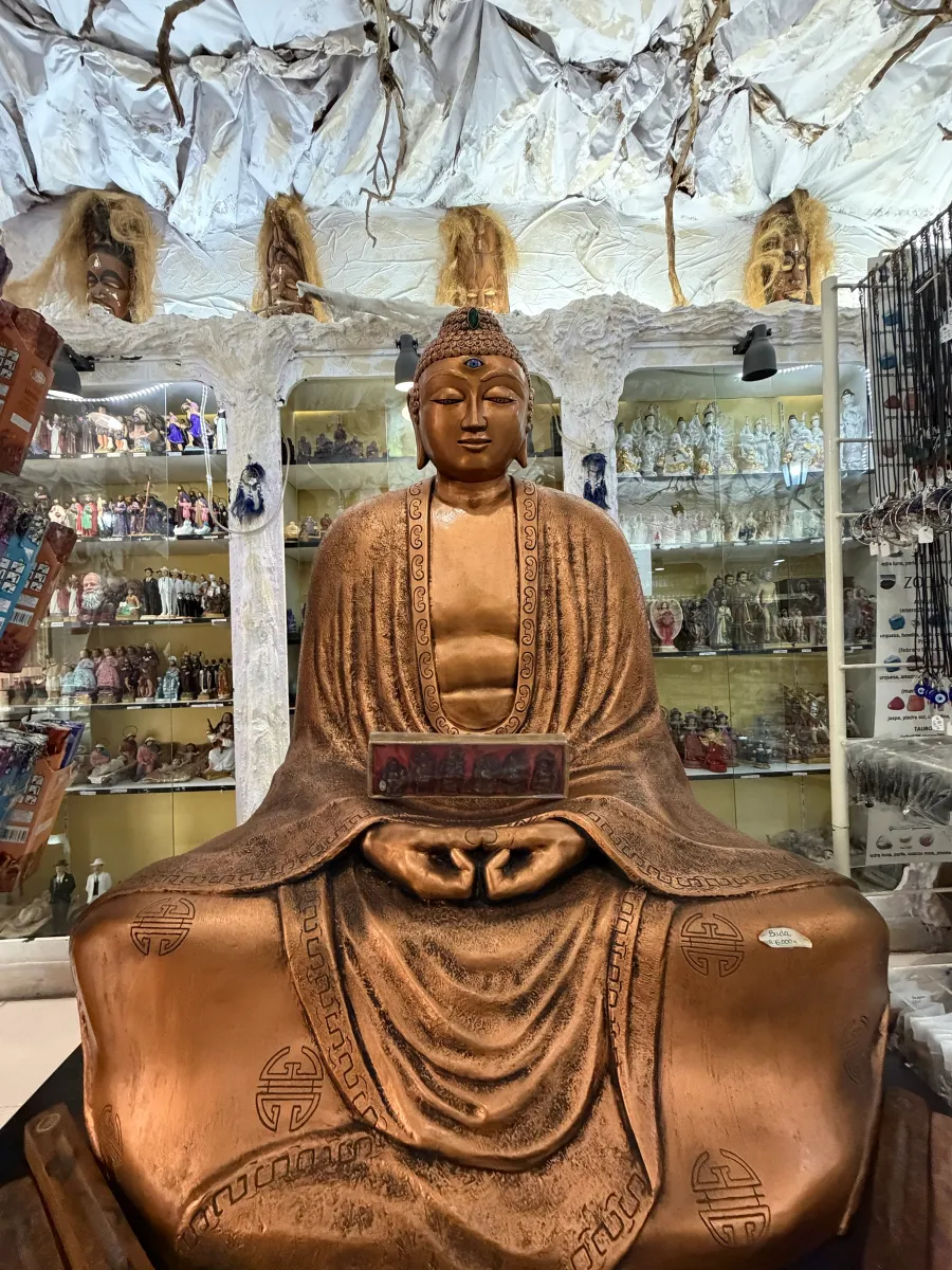Buda de bronce sentado entre las vitrinas de la tienda