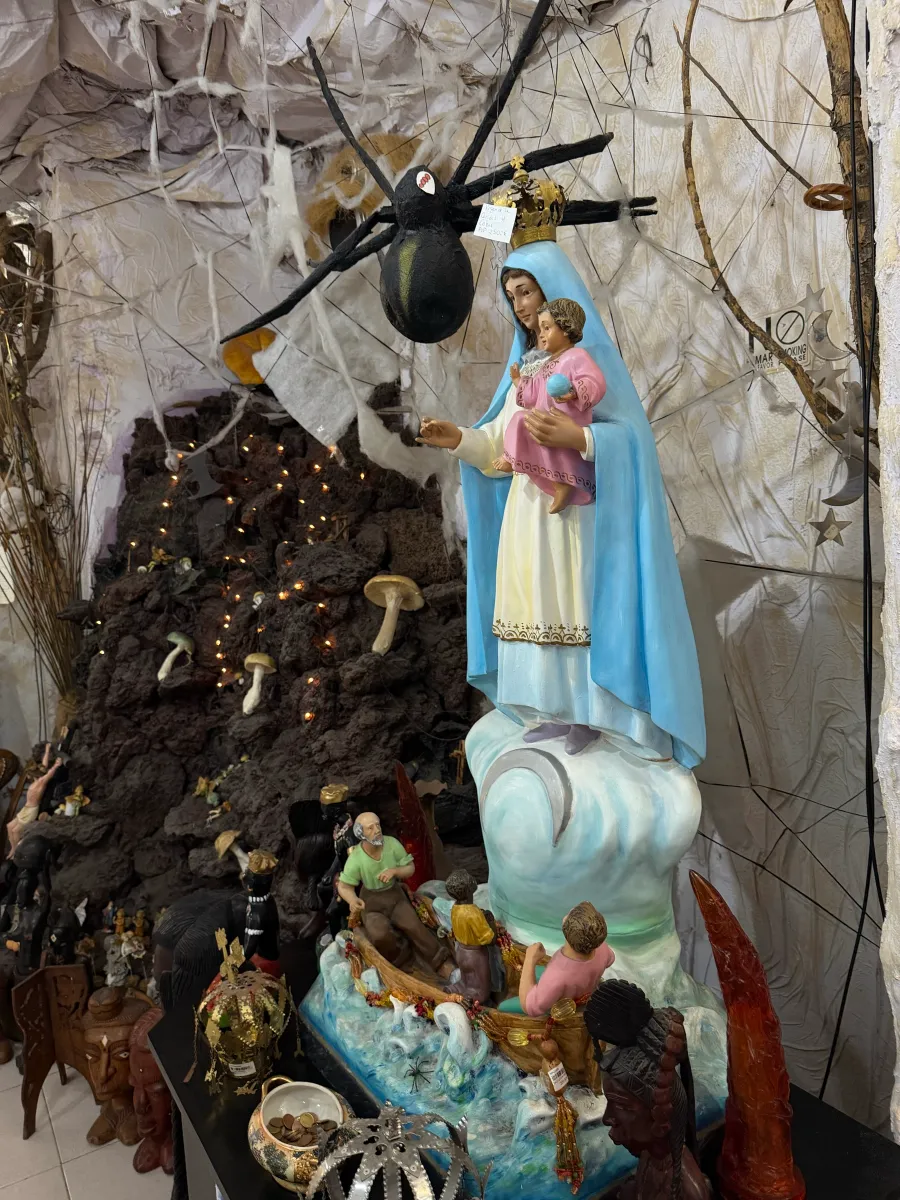 Virgen con el Niño sobre una barca con figuras, junto a la roca volcánica de la tienda